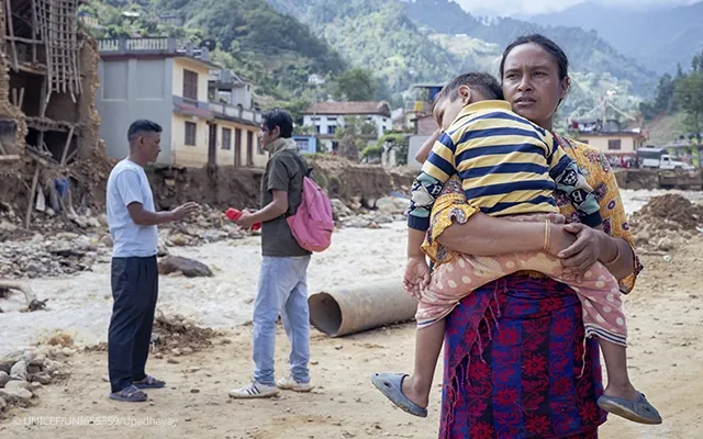 Criança no colo após enchente no Nepal