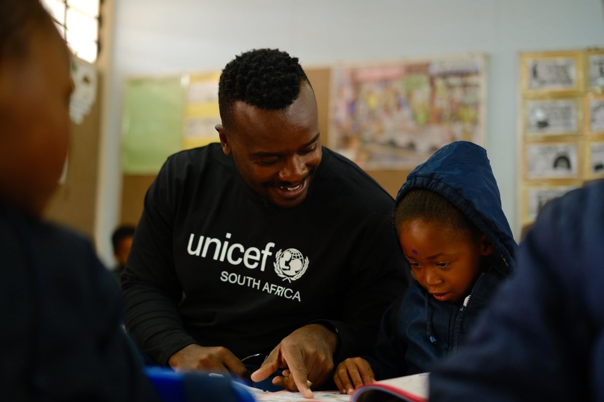 UNICEF Education Specialist, Engenas Senona and a learner reading a book