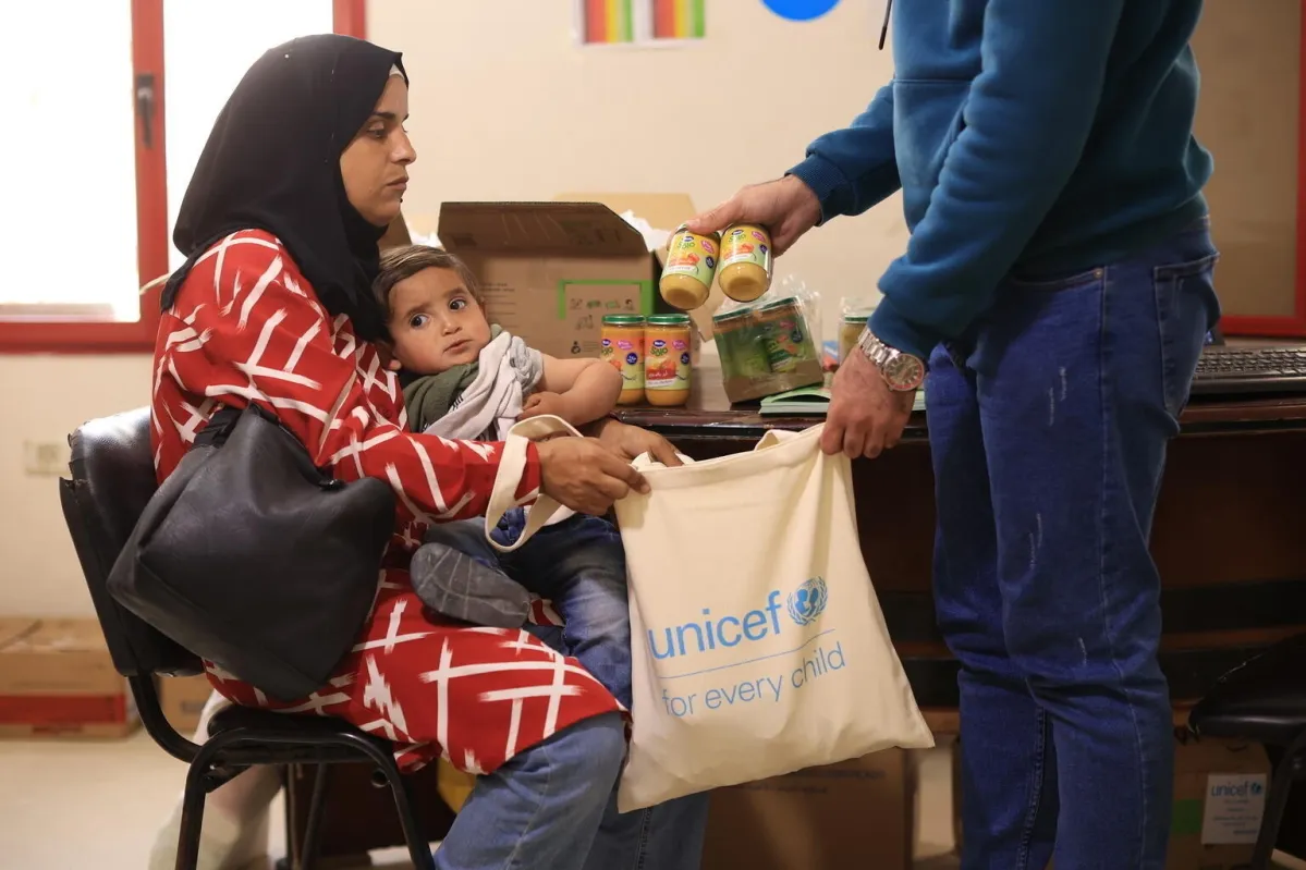 Madre con su bebé recibe apoyo nutricional de UNICEF, garantizando alimento y salud en contextos de emergencia.