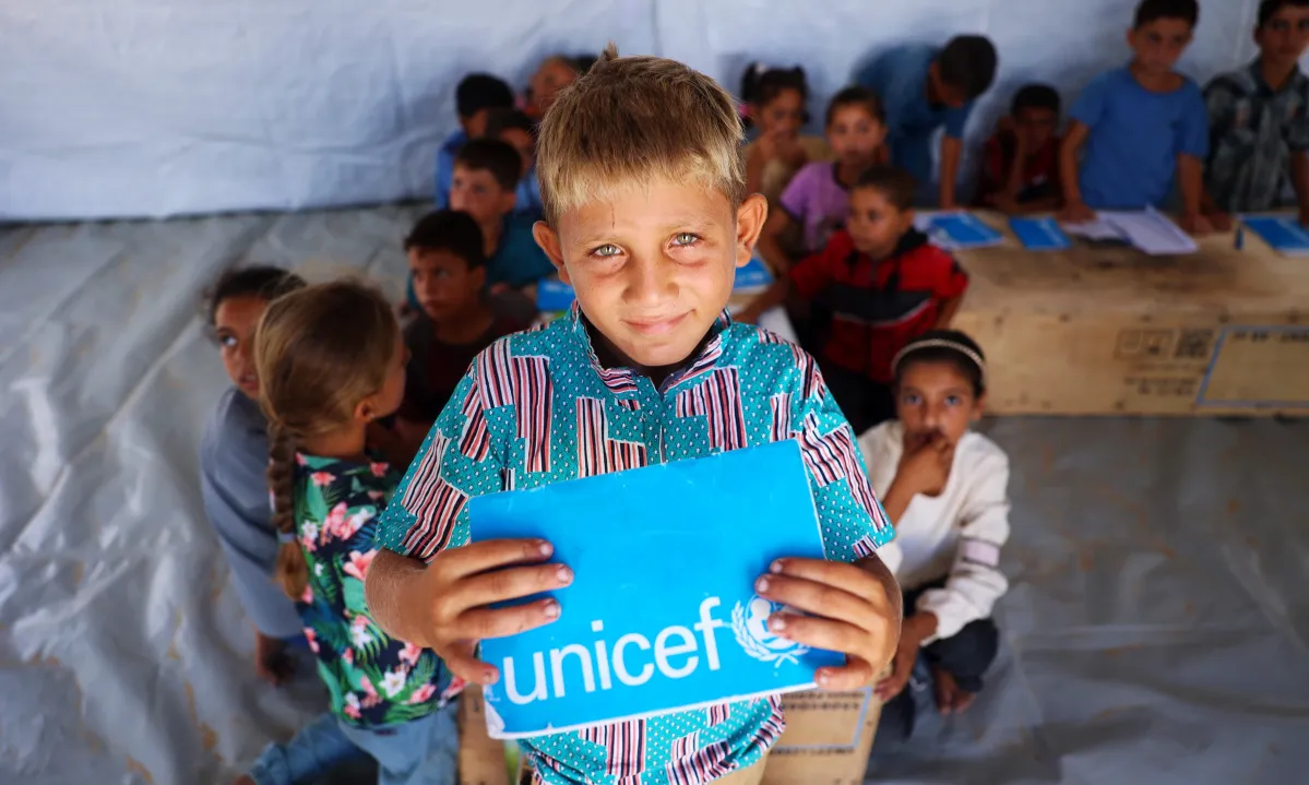 Niño en un espacio de atención de UNICEF sostiene su libreta, recibiendo apoyo psicosocial en medio de la crisis en Gaza.