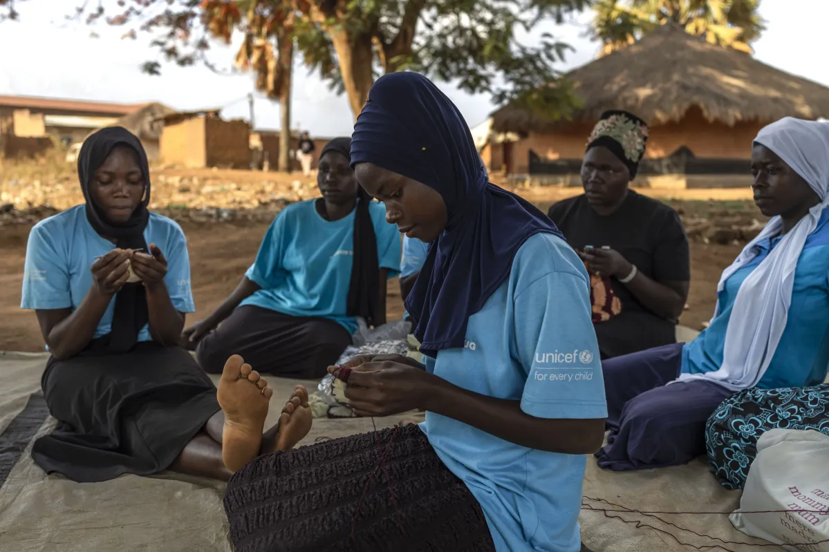 Jovenes se sientan a tejer y compartir en comunidad en Uganda. UNICEF. 