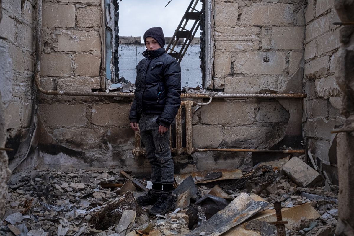 Danylo stands in the ruins of his home