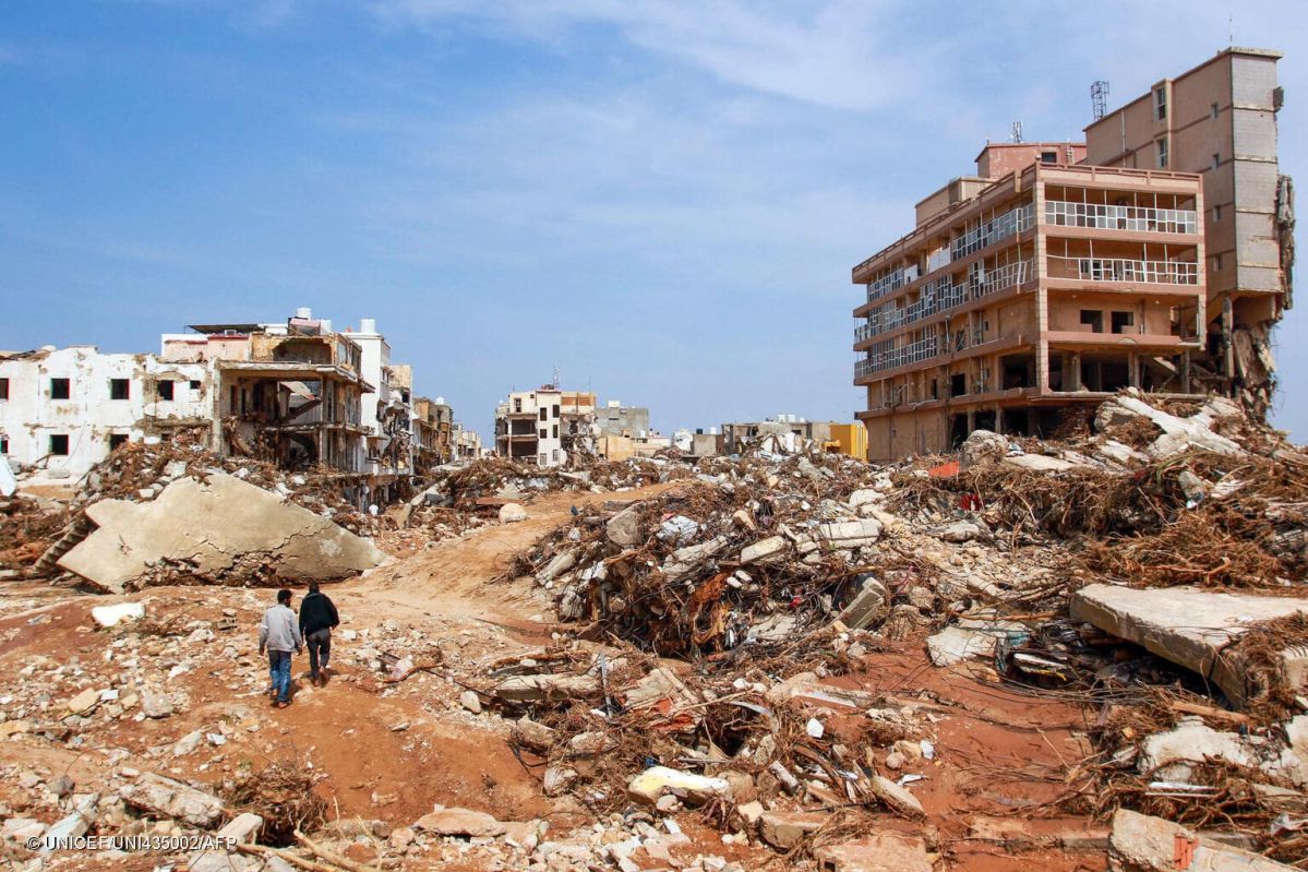 Men walk past debris of buildings damaged by flash floods in Derna, northeastern Libya, on Sept. 11, 2023. © UNICEF/UNI435002/AFP 