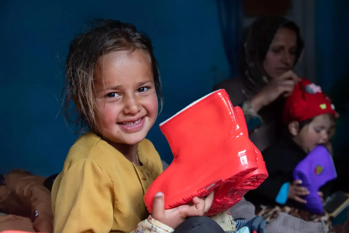 Sahar, 6 years old, holds a new pair of boots from a UNICEF winter clothing kit on 14 March 2023 in Panjshir Province, Afghanistan.