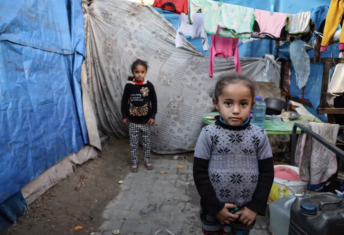 4-year-old Maria, pose for a photograph at their family's makeshift tent in a shelter for internally displaced persons in Rafah, southern Gaza Strip.
