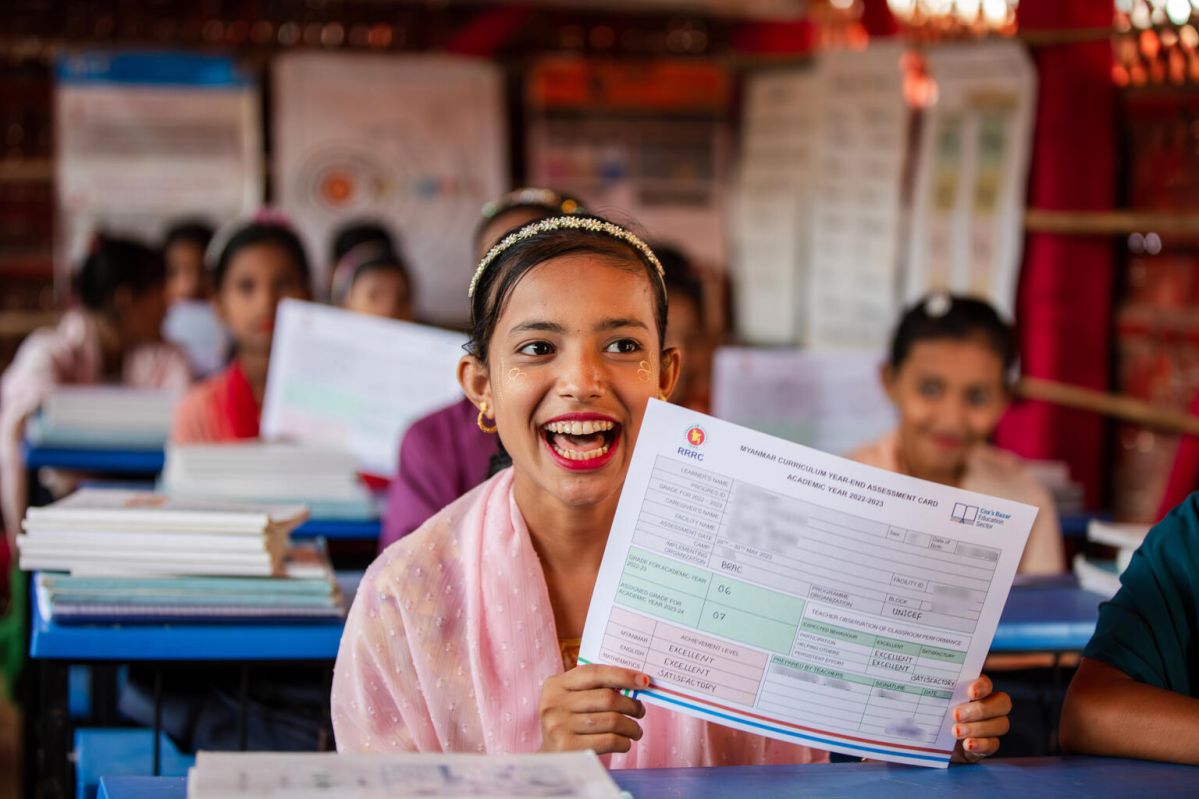  Kosmida, 15, holds up the first year-end assessment card that she has ever received at a UNICEF-supported learning centre