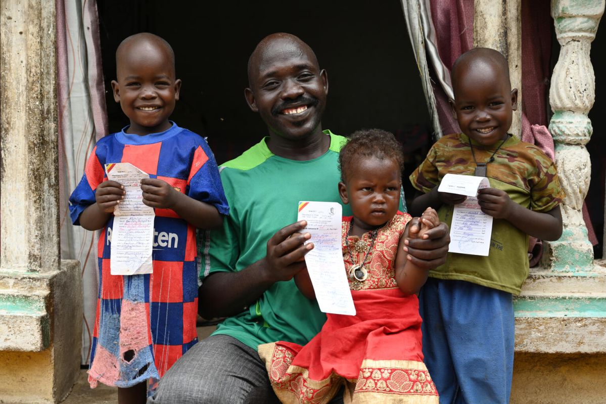A father and his three children holding their birth certificates